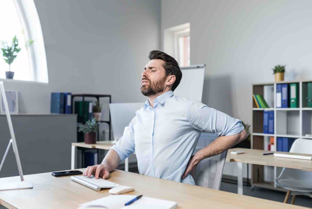 Persona trabajando sentada con molestias en la espalda baja